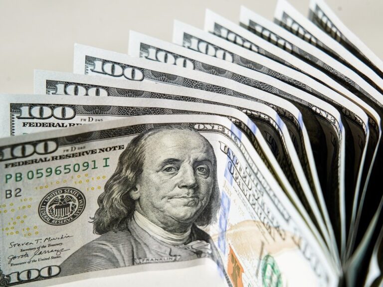 Billetes de dólar estadounidense sobre una mesa con calculadora y celular